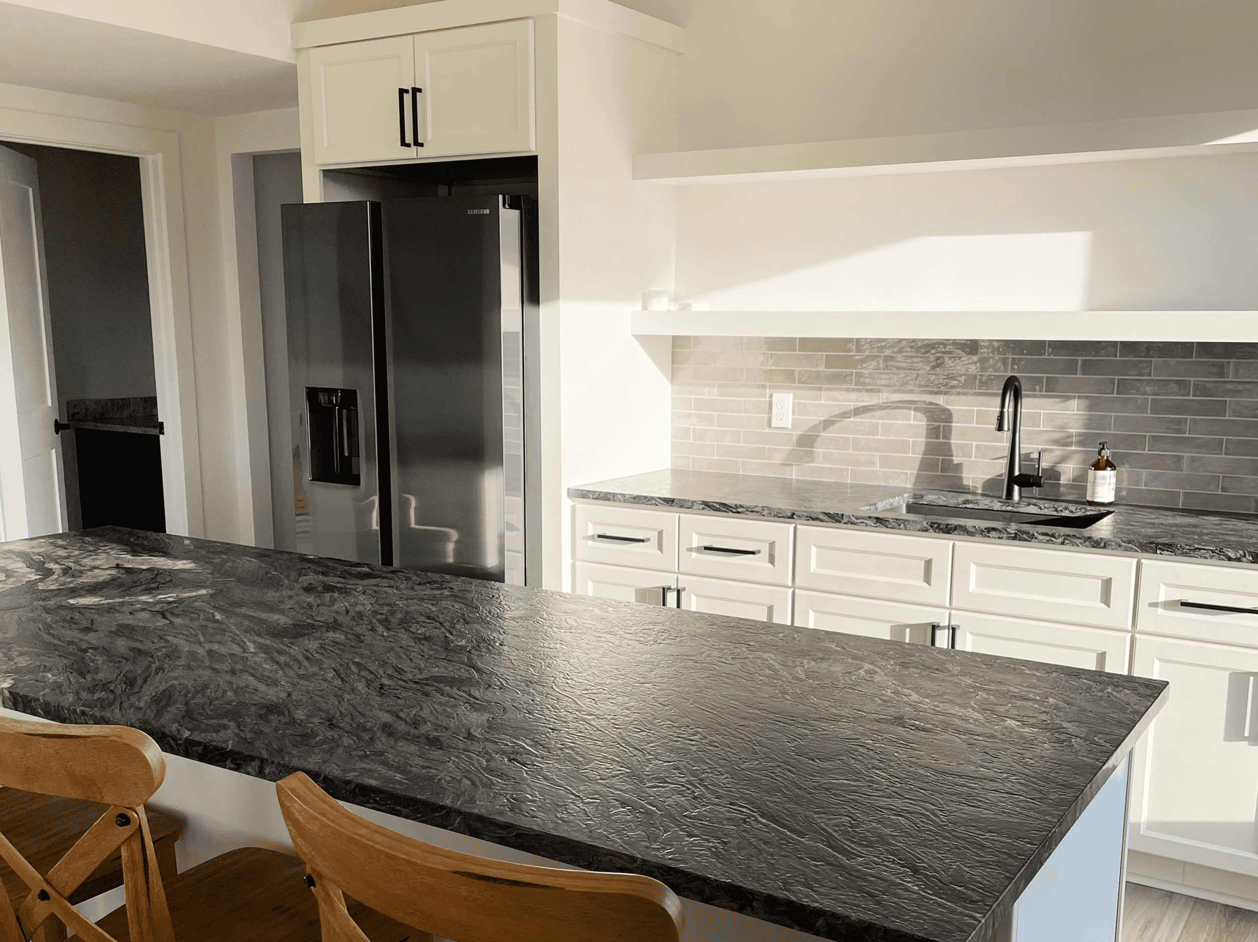 Contemporary kitchen with black refrigerator, white cabinets, and granite countertops.